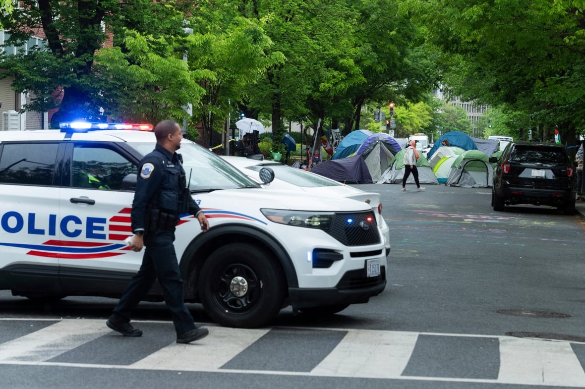 A policeman is shown next to the police car in an urban.