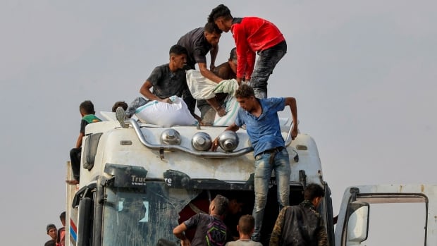 Palestinians scramble to collect aid supplies from a truck.