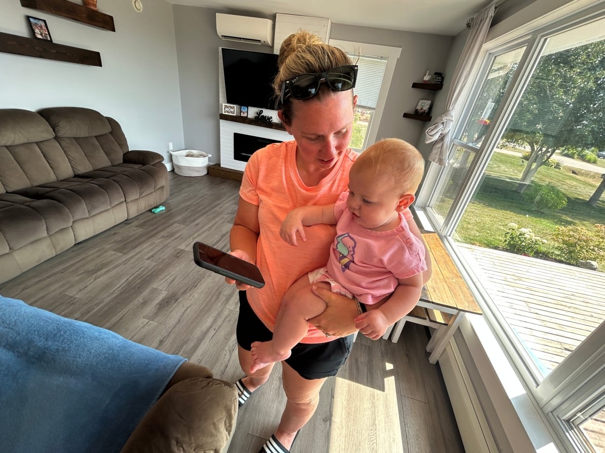 Sam McKendrick holds her daughter in her home, She said bad cells service is a  huge problem. 