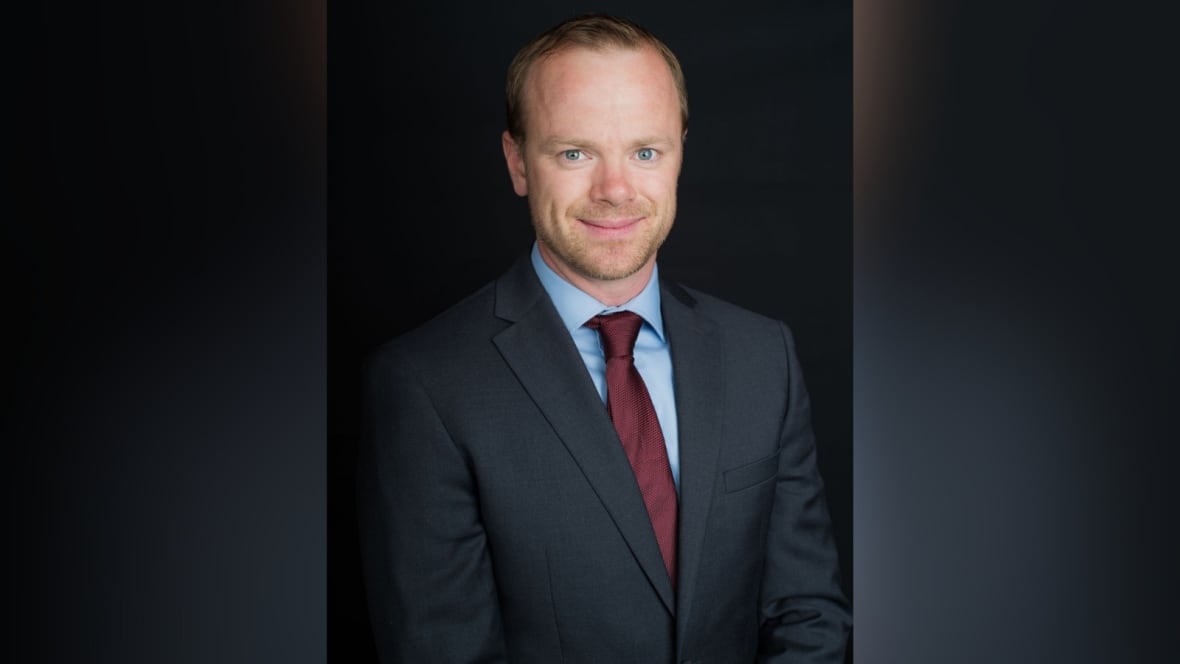 A headshot of a man in a suit.