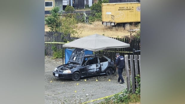 a burnt car being photographed by police