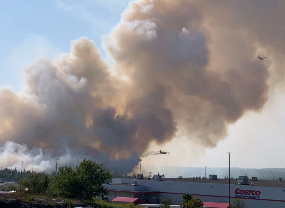 The smoke is located in the air while two planes pass. A commercial building is in the foreground.