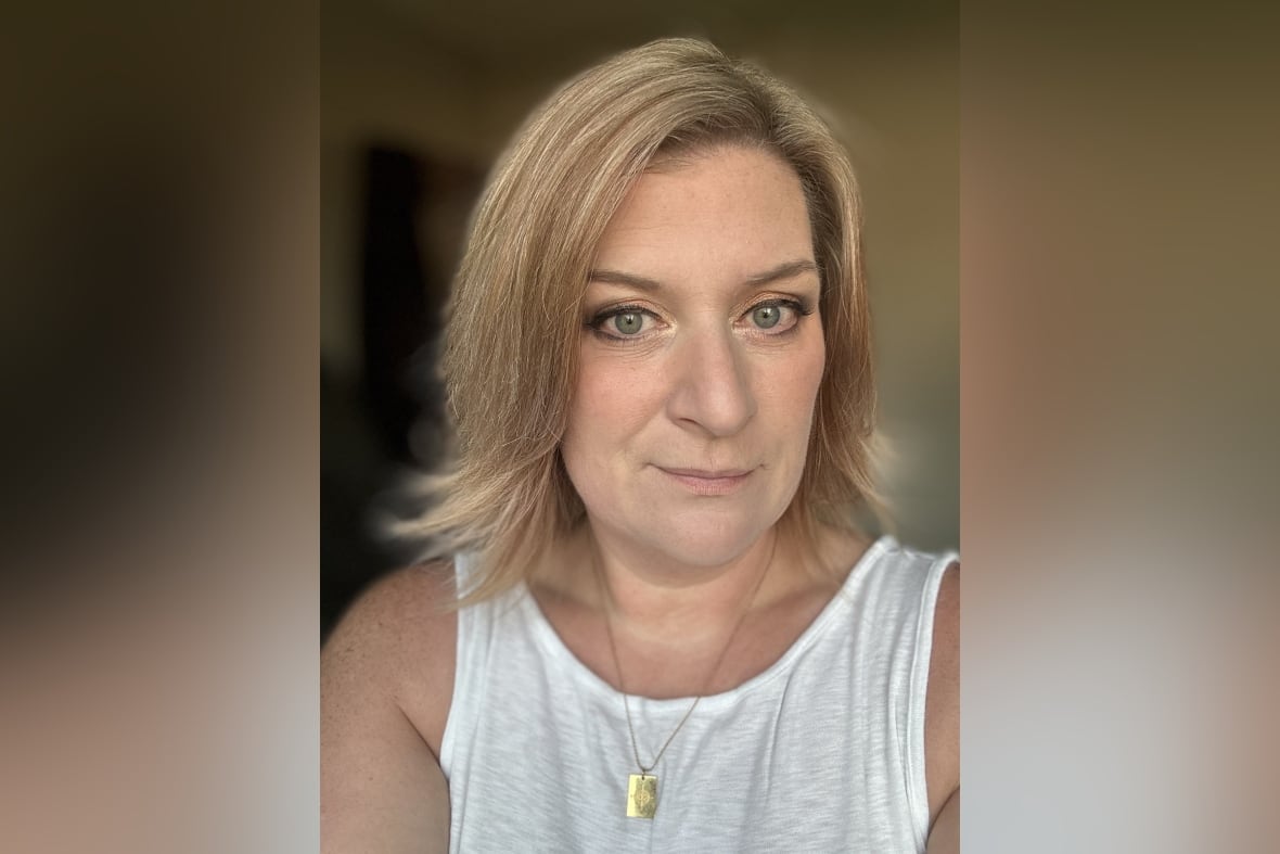 Woman with blonde hair and light eyes wears a white tank top shirt
