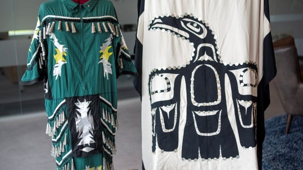 A dark green jingle dress, white and black blanket and suitcase