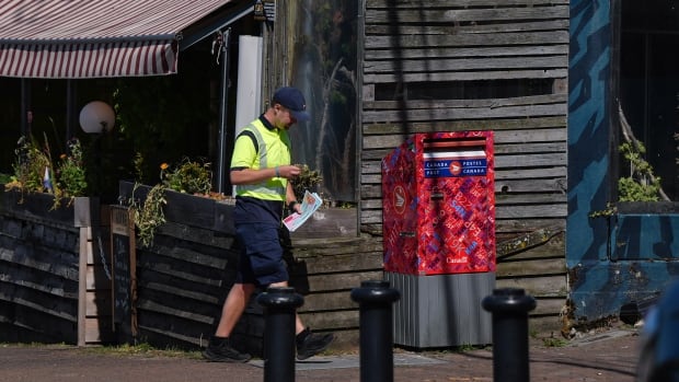 Canada Post employee prepares to check a street letter box