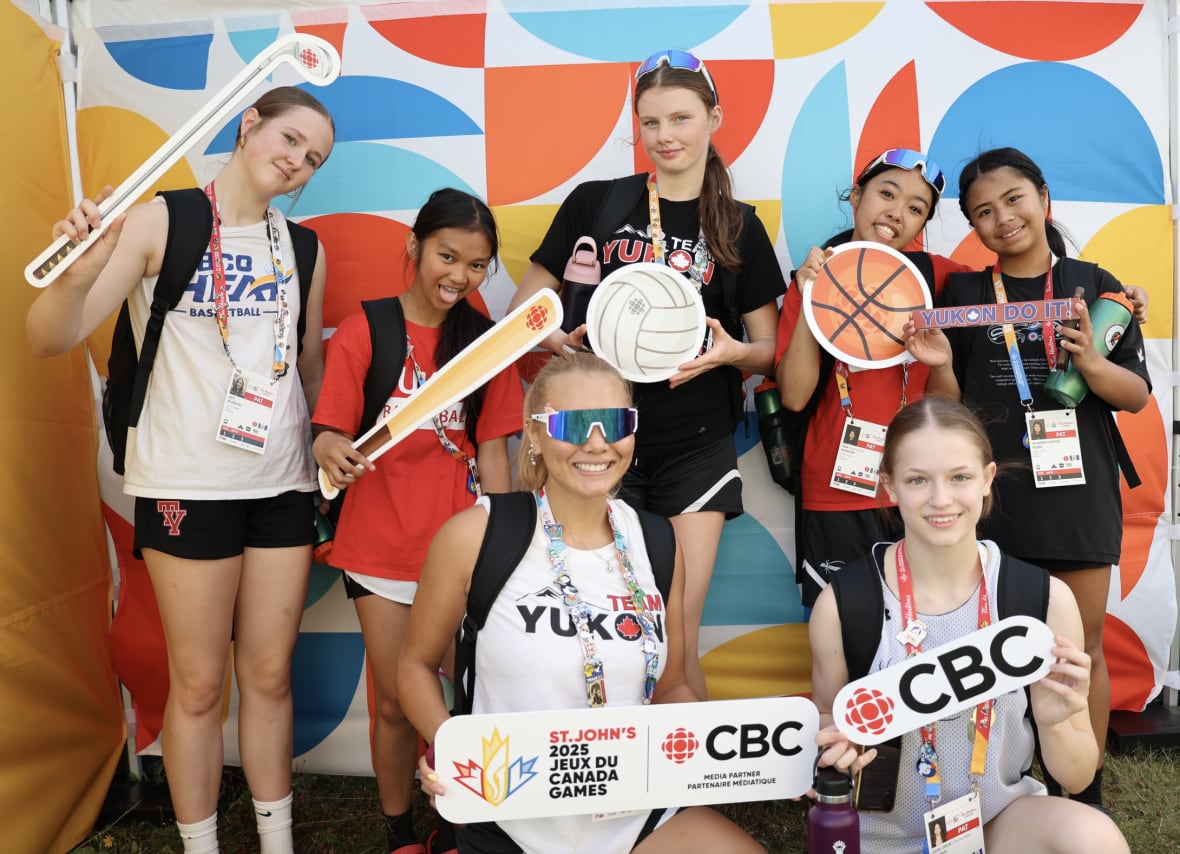 Seven young female athletes hold up props and strike a pose in the CBC Pop-Up Photo Studio at the 2025 Canada Games.