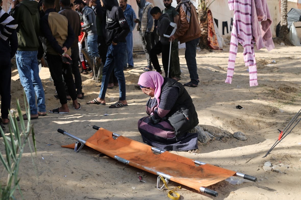 A woman reacts while people bury bodies of Palestinians killed in an Israeli strike, at the Nasser hospital premises as Palestinians cannot reach the cemetery due to the Israeli ground operation, in Khan Younis in the southern Gaza Strip, on January 22, 2024.