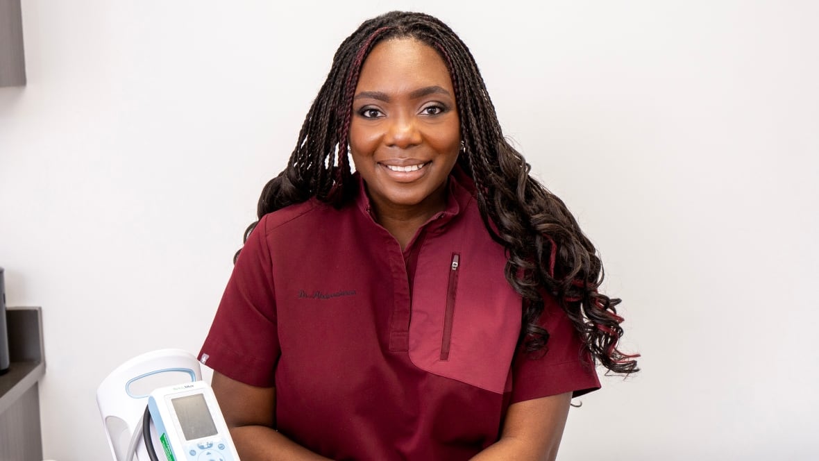 A woman smiles while wearing scrubs. 