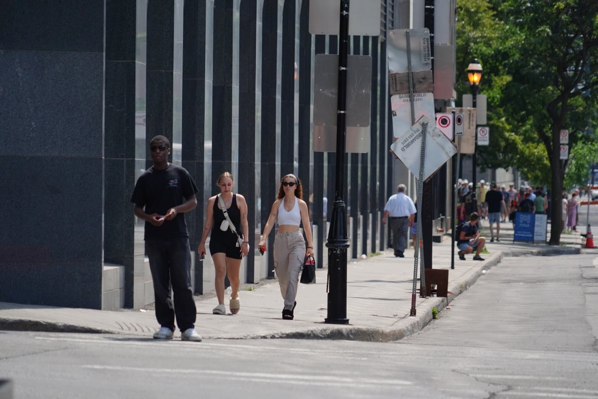 Pedoni passeggiano nella Vecchia Montreal in una giornata di sole.