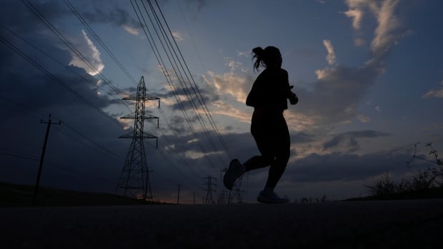 A silhouette of a person running at dusk