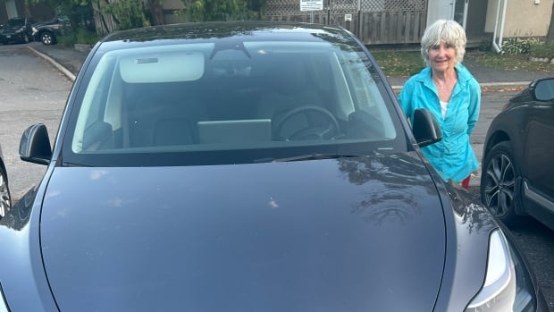 Carolyn Inch of Ottawa bought a used Tesla Model 3 recently, and started getting suggestions from friends, family and neighbours that this choice might be bad for the planet. Woman beside Tesla car viewed from the front