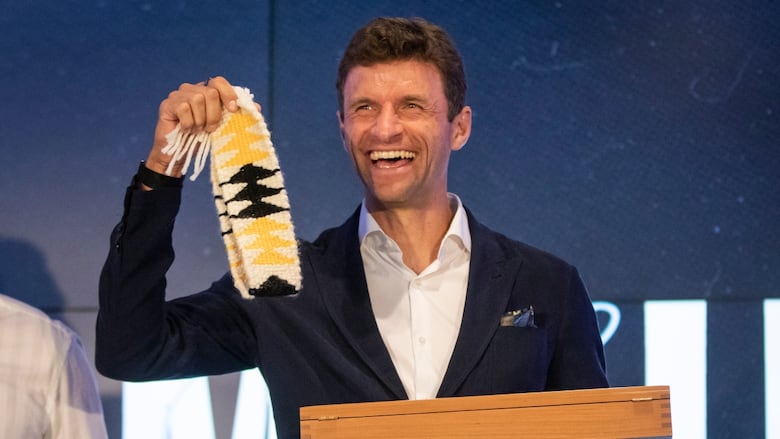 A smilling man holds up a headband.