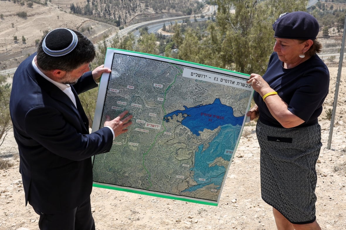 Israeli Finance Minister Bizalil Sottic and a woman bearing a map.