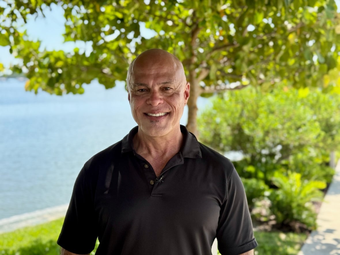 A man in a black shirt stands outside. 