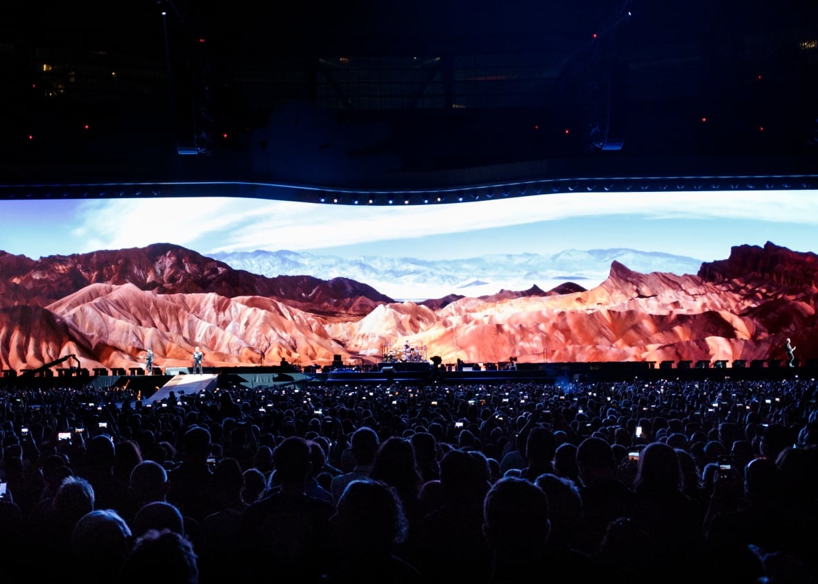 A photo of audience members looking at a lit-up screen with mountains ahead.