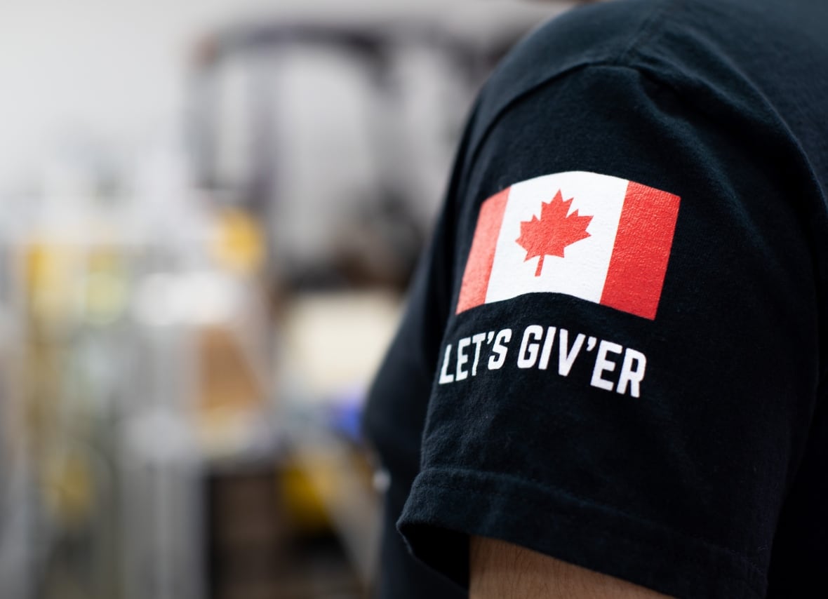 The sleeve of a black t-shirt is shown with a patch that reads, "Let's Giv'er."