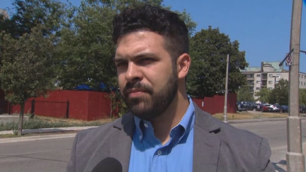 Jordan Cristillo, spoke to CBC outside of a court hearing for Jaiwin Victor Kirubananthan, who is charged in the death of his brother Andrew. a man in a blue shirt and grey jacket stands outside.