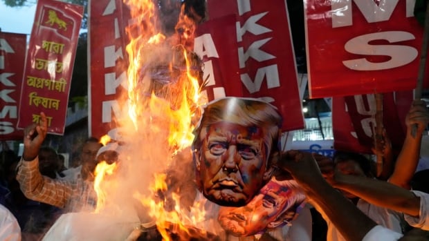 A paper mask of Donald Trump goes up in flames at a protest