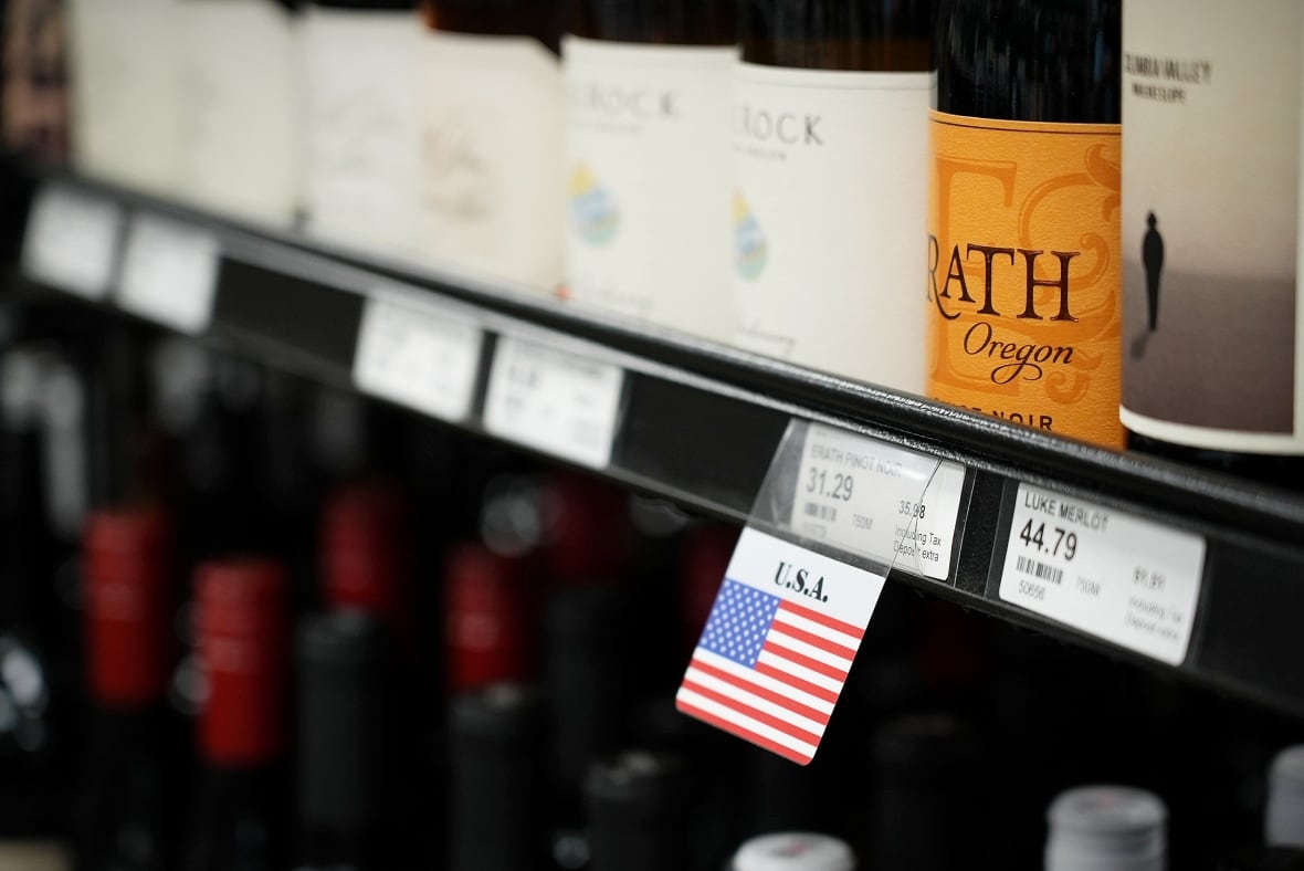 A USA flag underneath a bottle of wine on a store shelf 