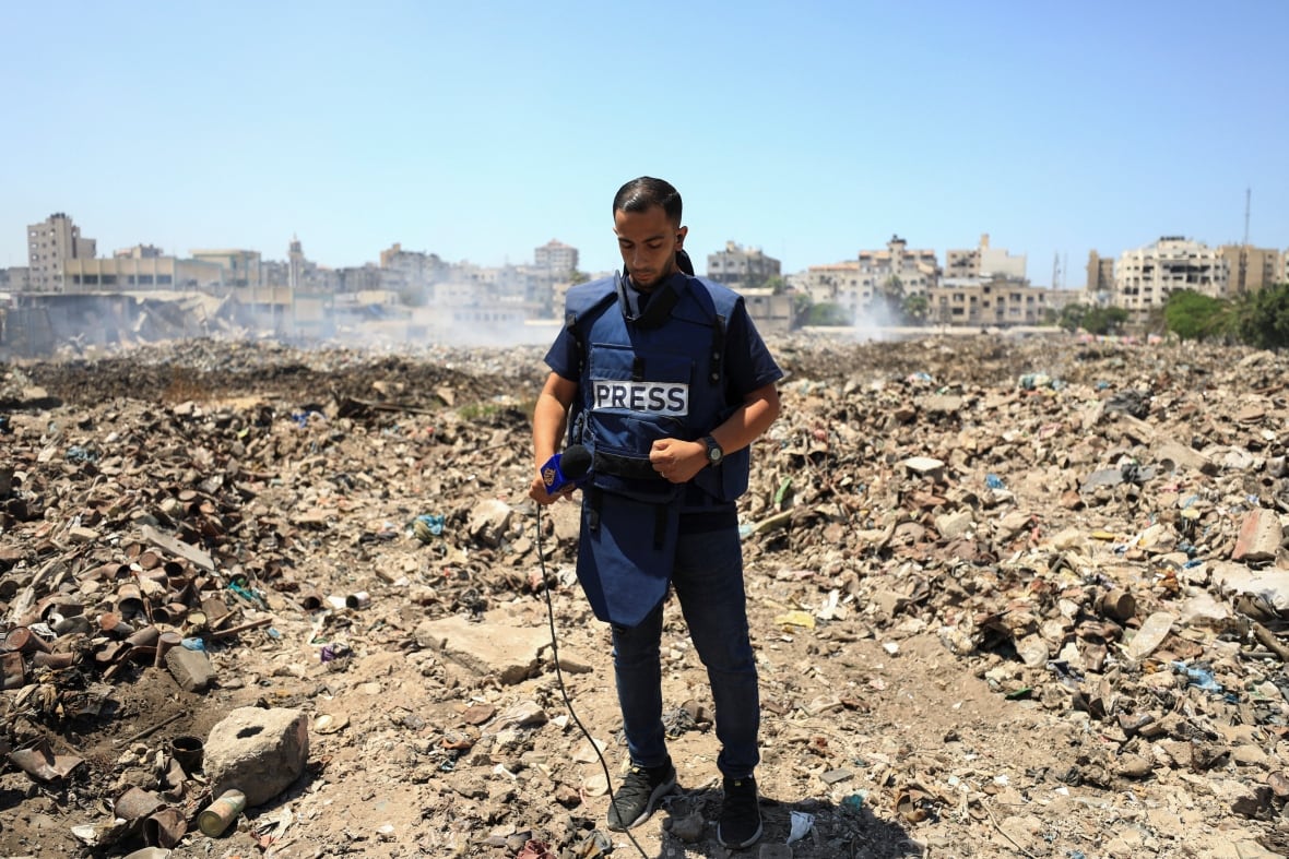 Al Jazeera journalist Anas Al Sharif, who was killed in an Israeli strike on August 10, 2025, stands at a landfill as he reports the news in Gaza City on August 13, 2024. 
