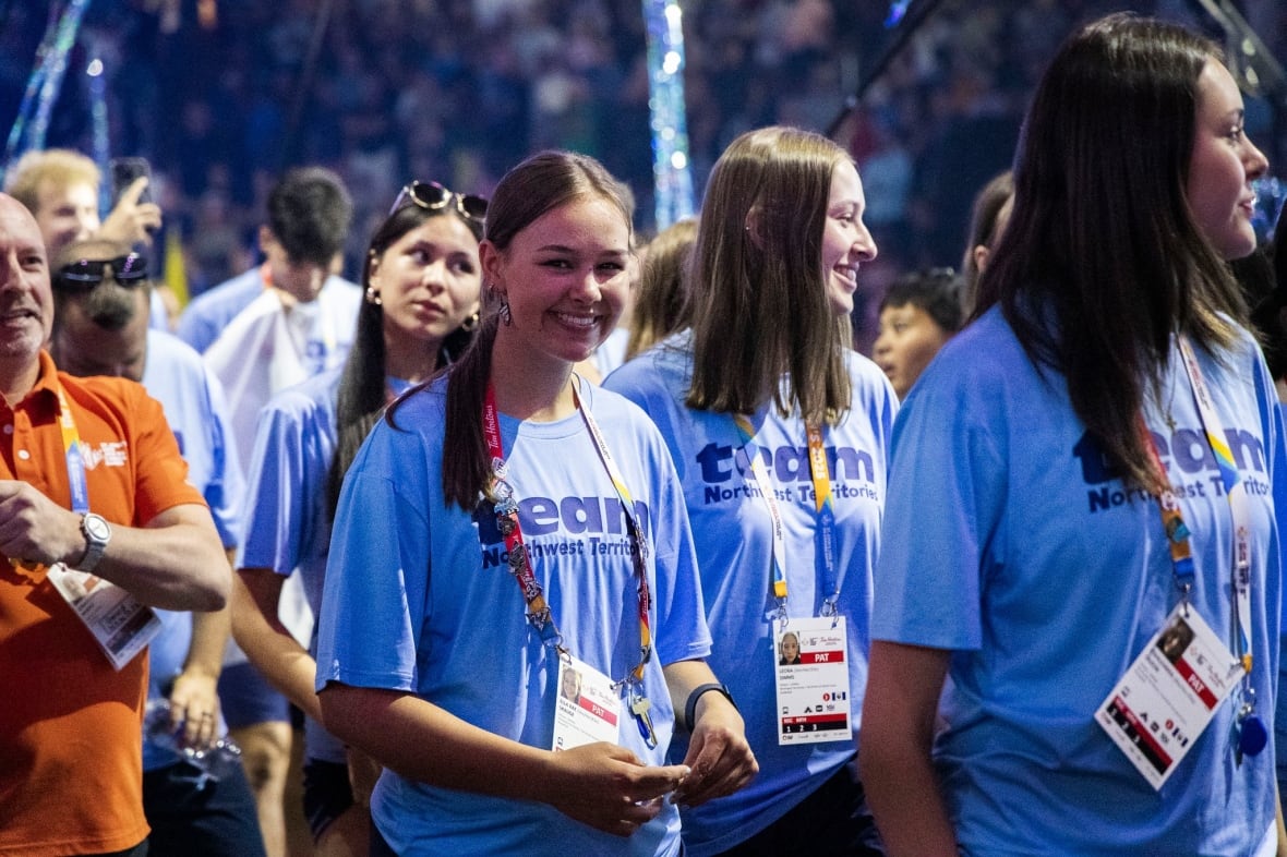 Young women in blue t-shirts in a parade in a stadium.