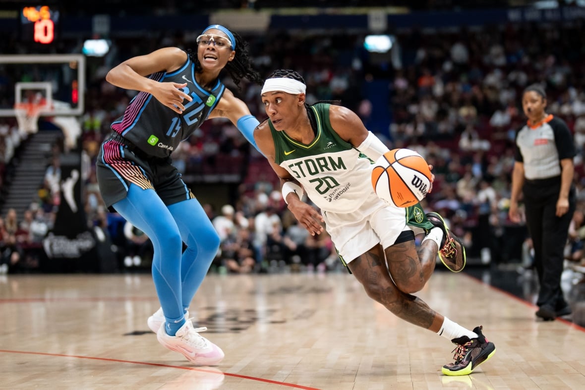 Two athletes dribble the ball in a basketball matchup.