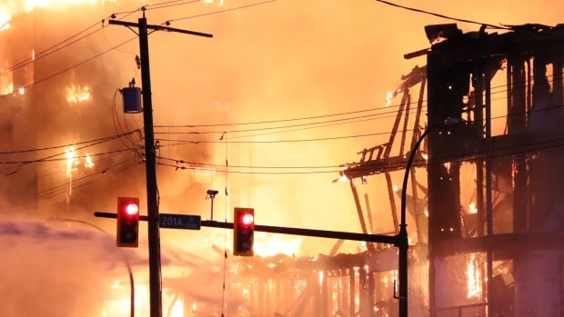 Large flames and an orange glow envelop an under-construction high-rise building.