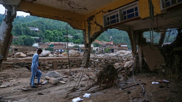 A person walks past a destroyed building.
