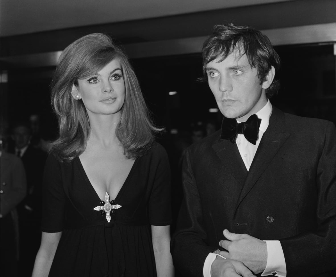 A man in a tuxedo and a woman in a dress are shown in a black and white photo from decades ago.