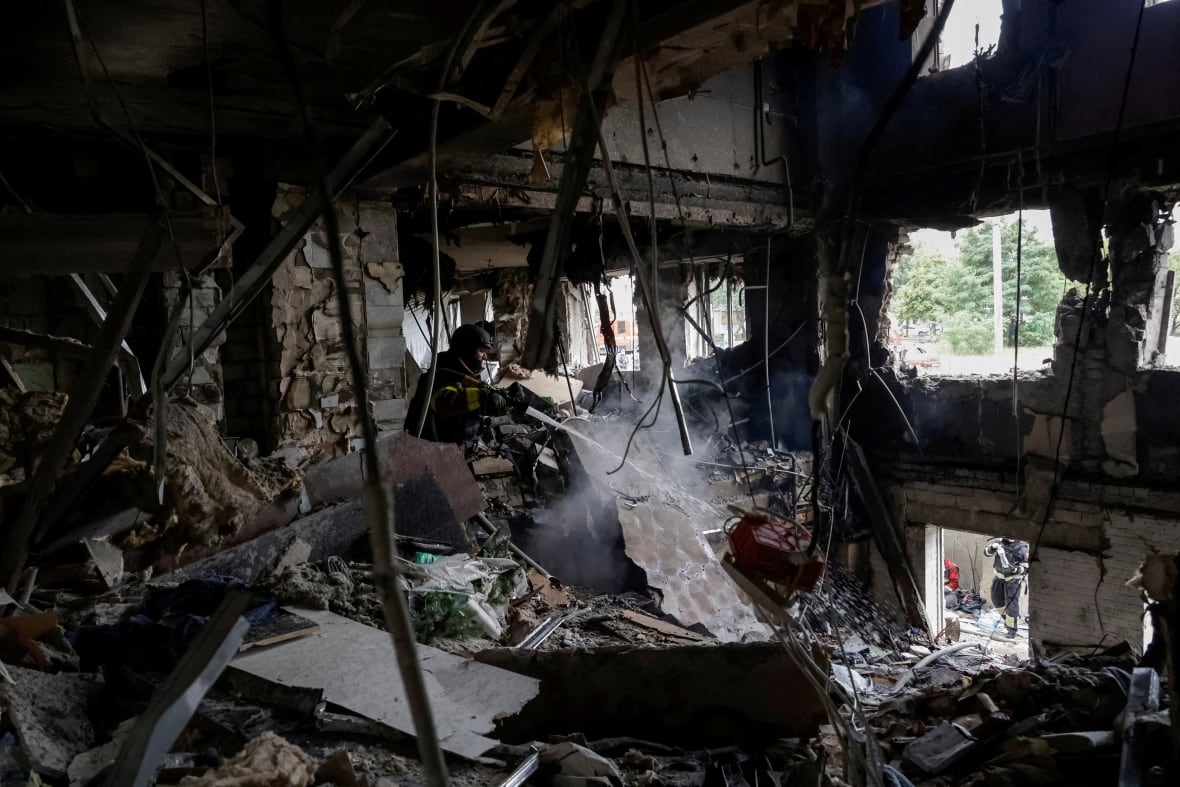 A firefighter appears inside the charred and destroyed room spraying room.