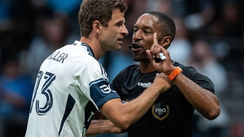 Soccer player and referee interacting with each other during the game.