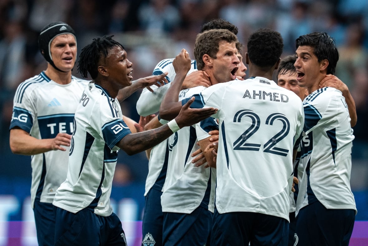 Soccer players get together and cheer in celebration after scoring.