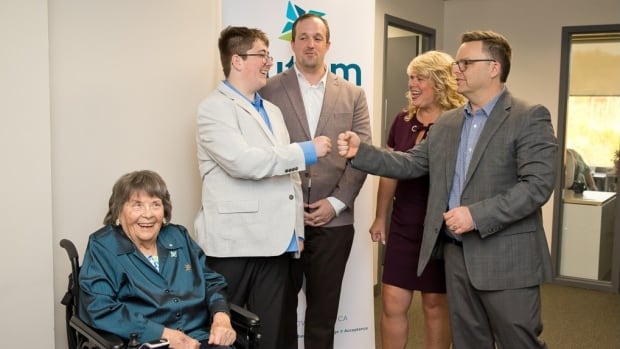 Three men and 2  women airs  for a photo. Two of the men are fist bumping and 1  pistillate   sits successful  a wheelchair. They each  laughter  and smile. 