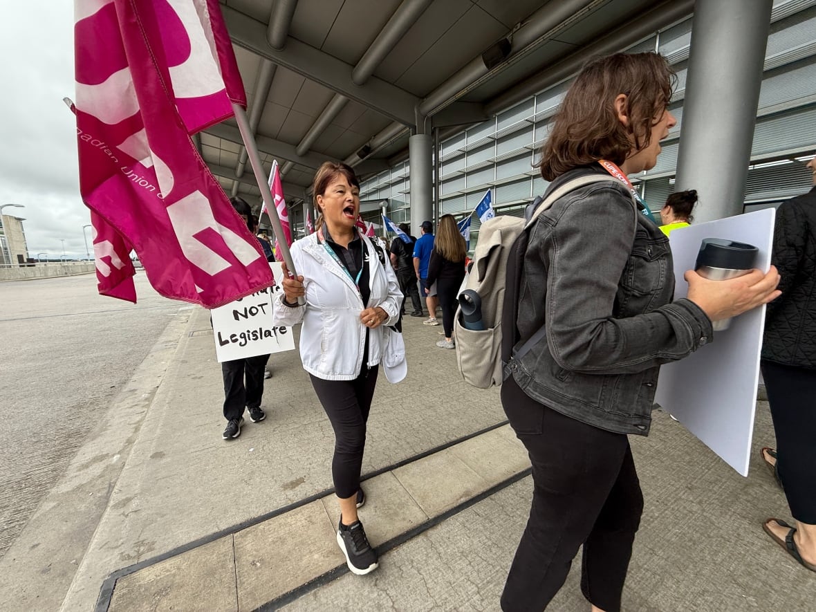 A row of people on strike walk in circles on the picket line.