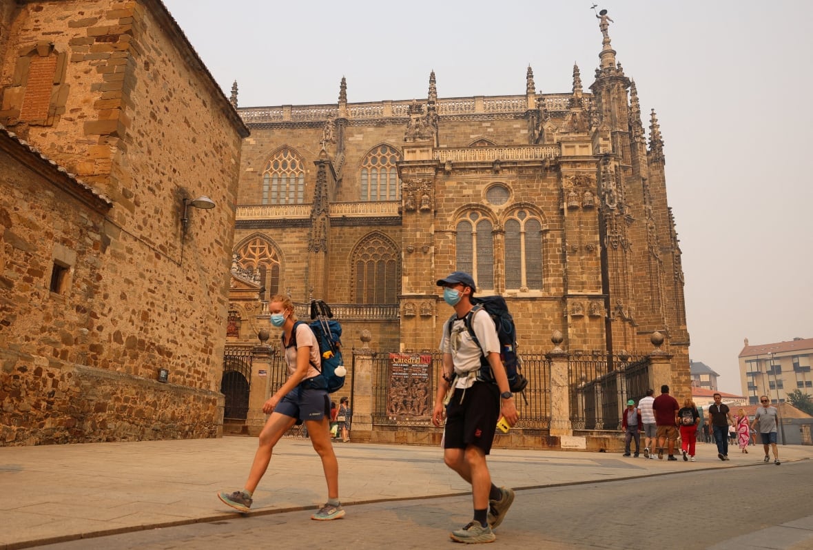 Pilgrims on the Camino de Santiago wear masks to protect themselves from wildfire smoke in Astorga, Spain.