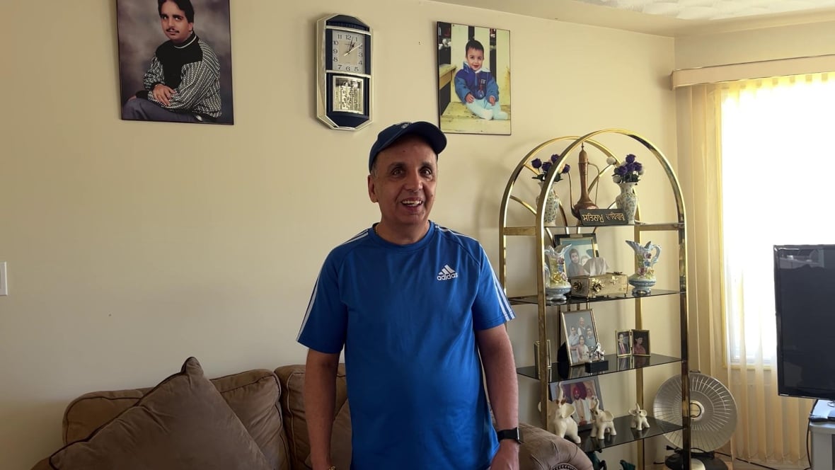 Surinder Takkar stands in his living room surrounded by photos of his family.