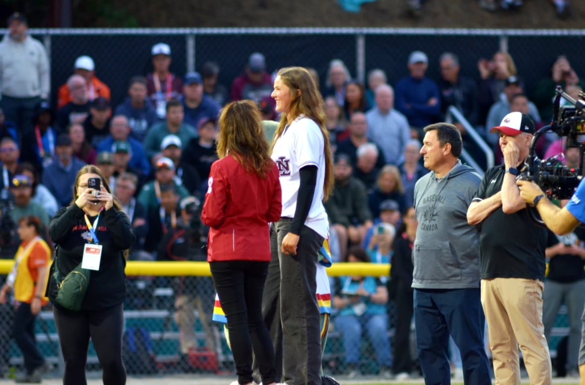 A group of people standing on a baseball field.