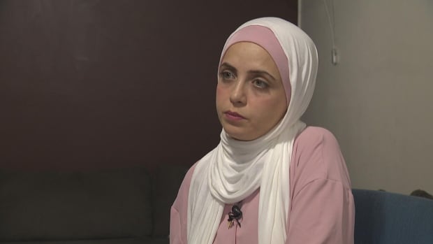 Nariman Ajjur, a Palestinian Canadian living in Surrey, B.C., says the visa applications for her family members have stalled. A woman in a hijab sits in a room.