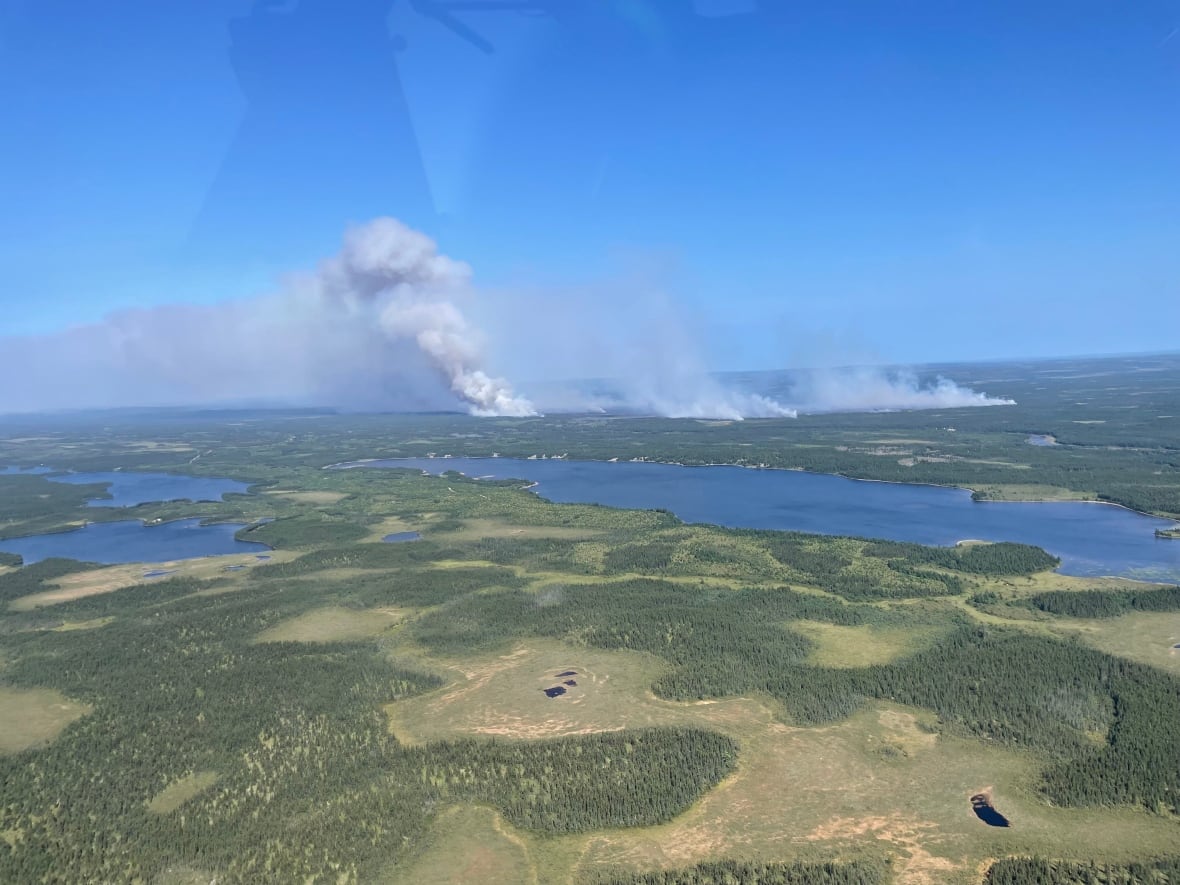A view of land taken from sky, with dark smoke coming from land.