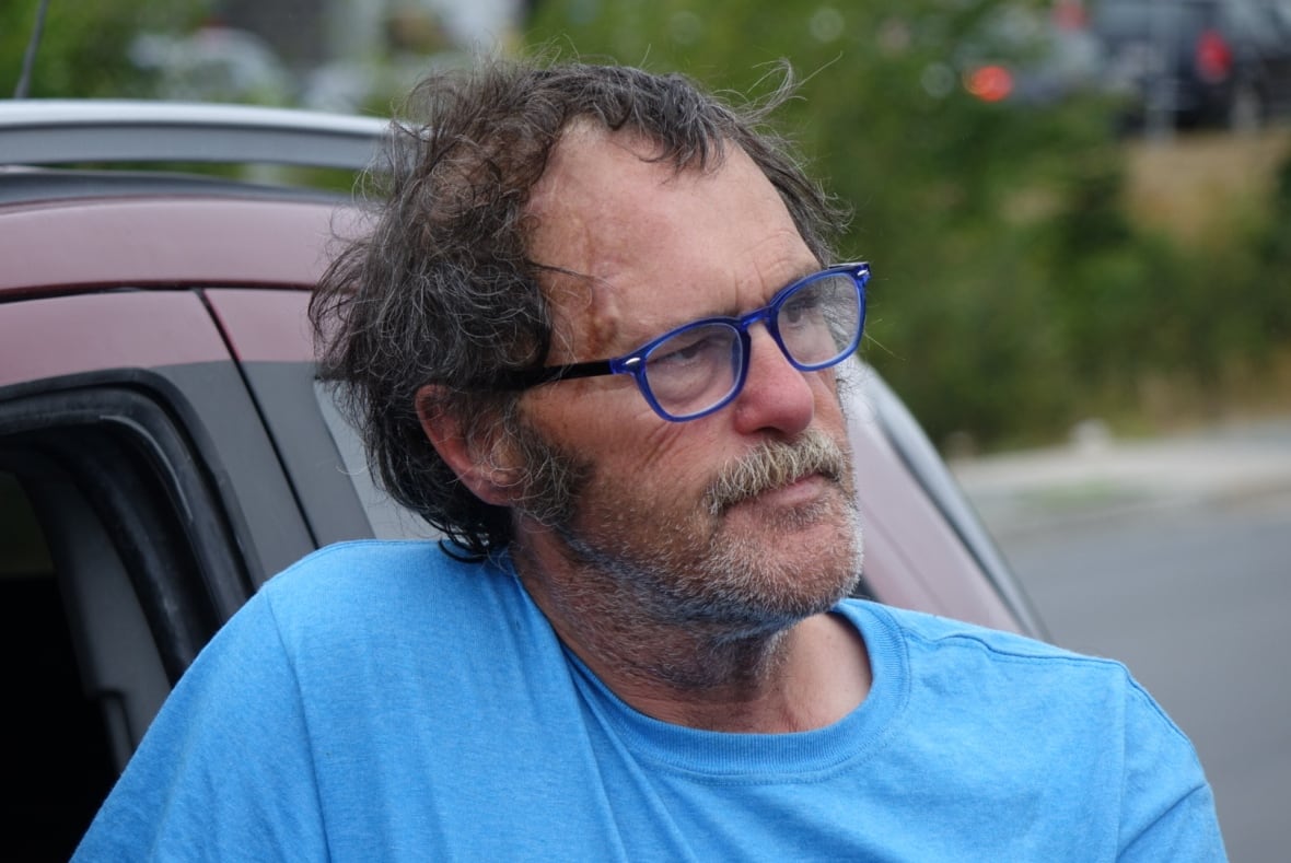 A man leaning against a car.