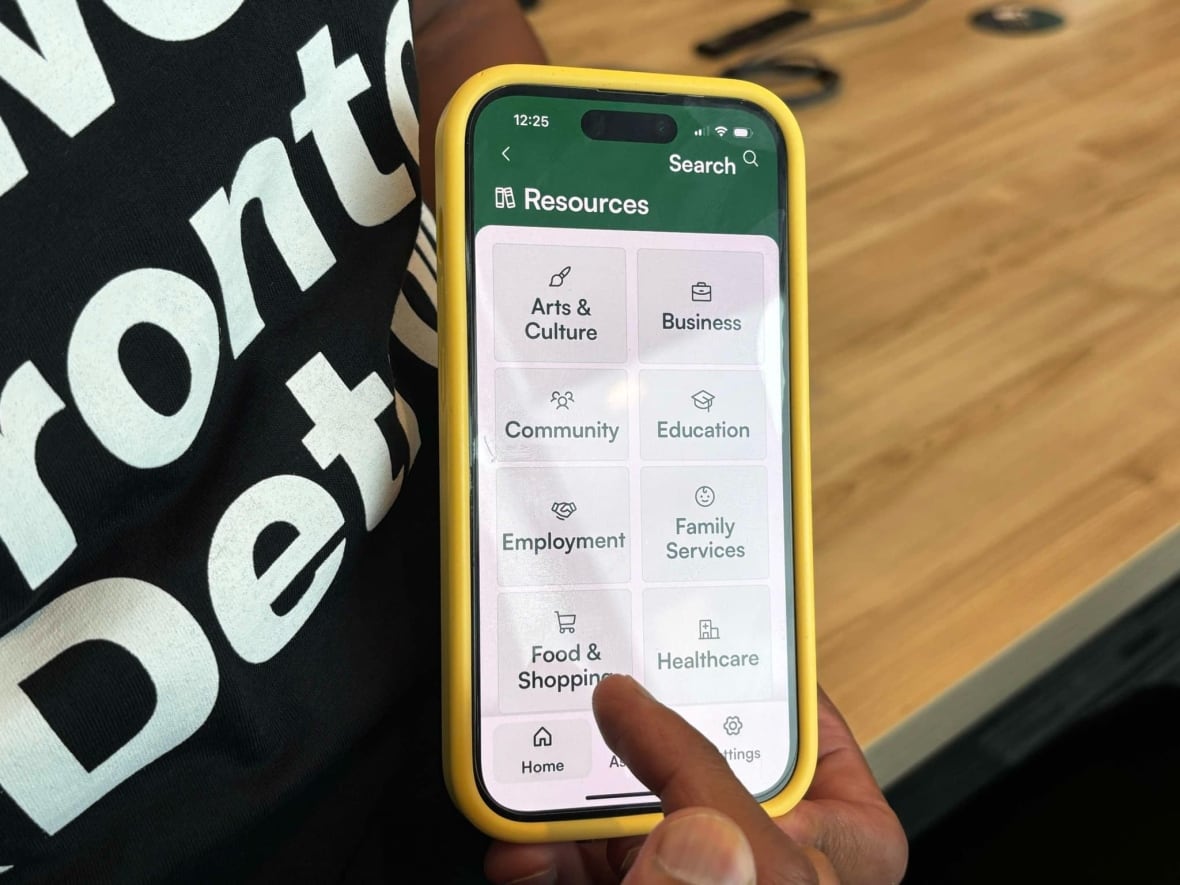 A finger points to a phone app that shows different buttons including "arts & culture," "employment" and "food & shopping."