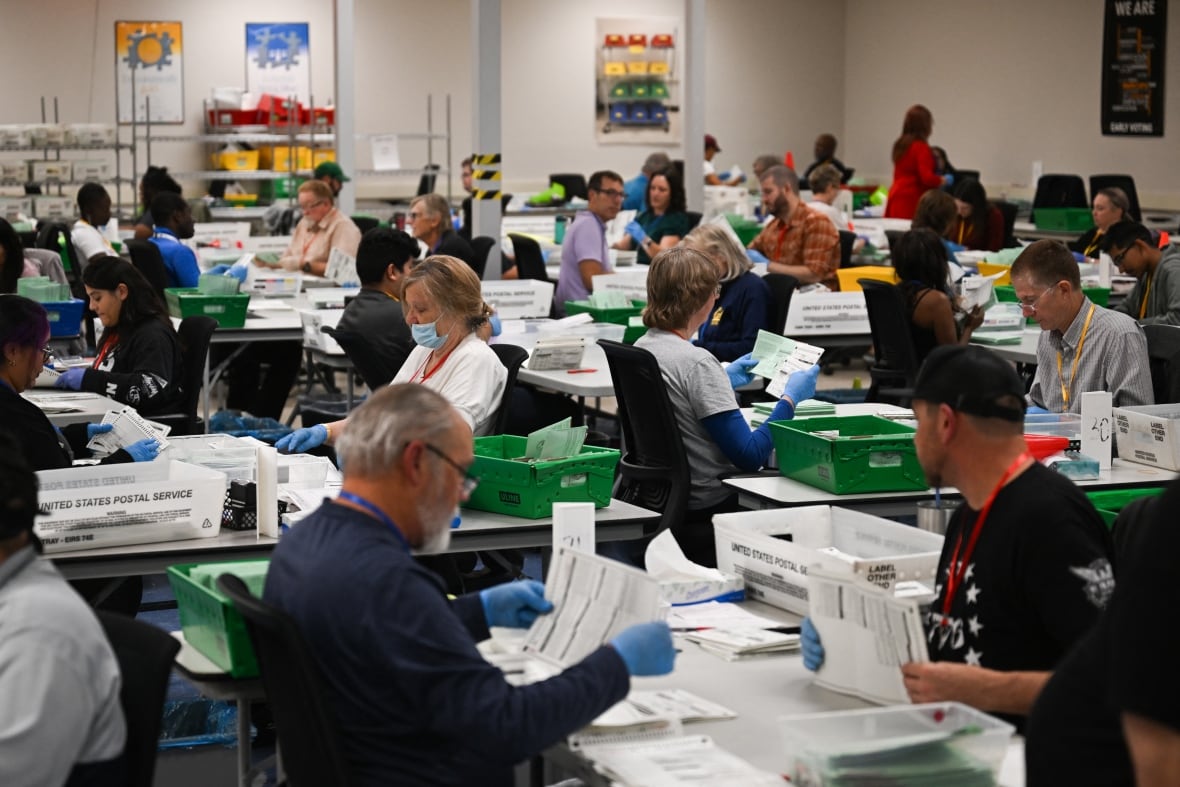 Pairs of election workers from different political parties open and inspect mail-in ballot envelopes containing voted ballots after they completed signature verification during processing inside the Maricopa County Tabulation and Election Center (MCTEC) on Election Day, November 5, 2024 in Phoenix, Ariz.