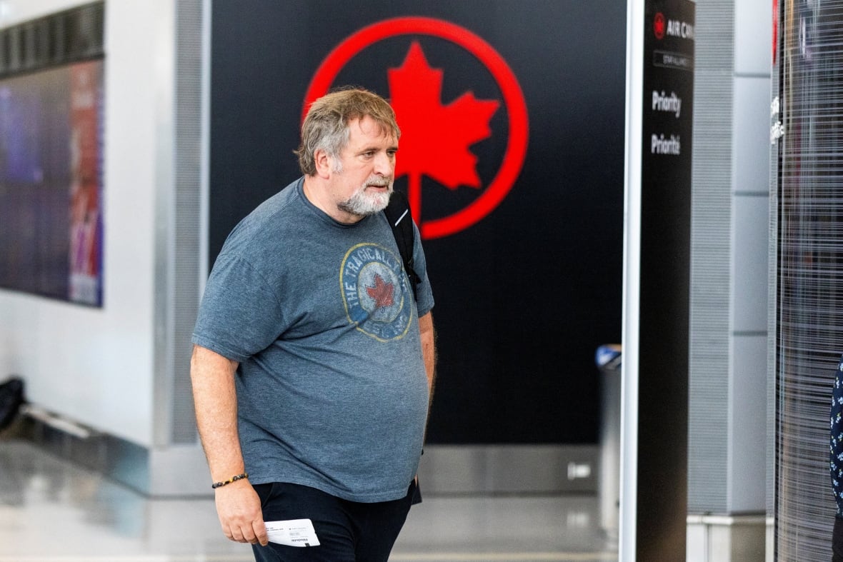 Uma pessoa em uma camiseta corre em um aeroporto, um ar em frente ao logotipo canadense.