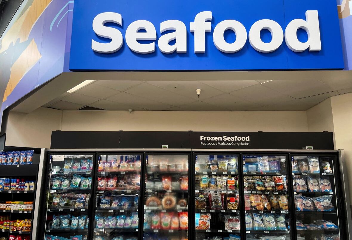 A large blue sign with white lettering "Seafood" It is displayed above the freezer filled with frozen goods. 