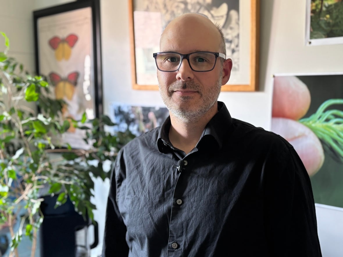 A man wearing glasses standing in his office.