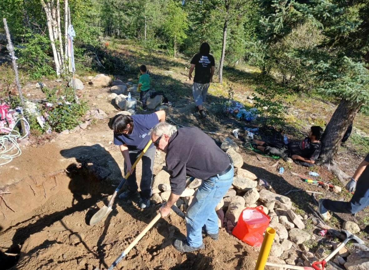 A group of people put shovels on the ground to dig a hole.