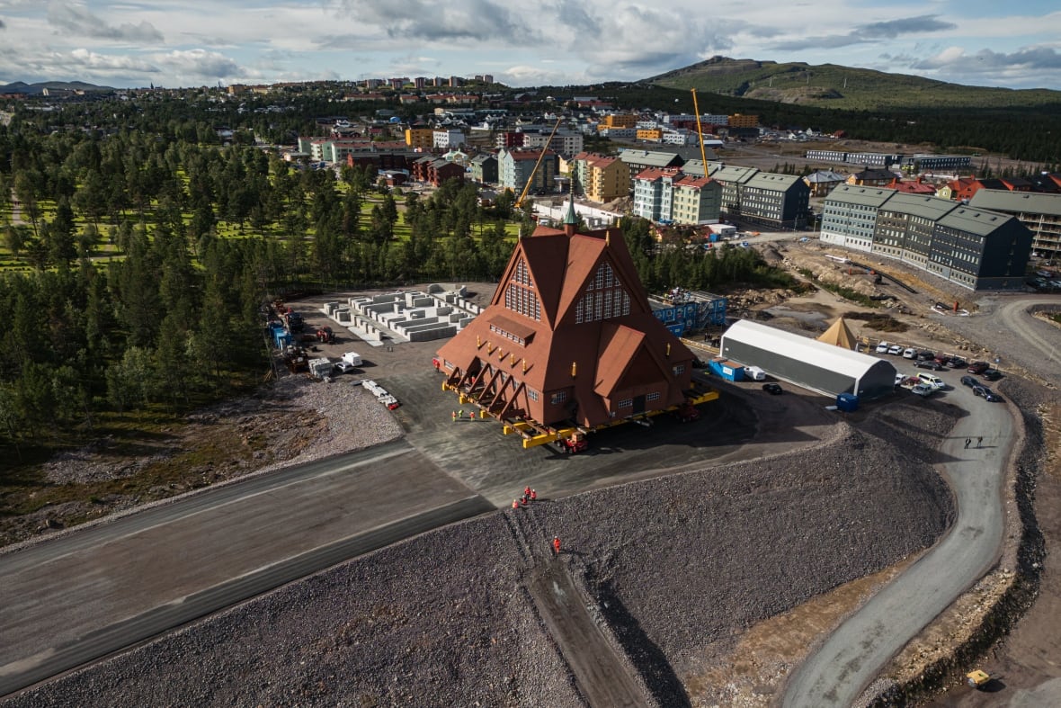 A large, brown A-frame church pictured from above in a freshly cleared lot