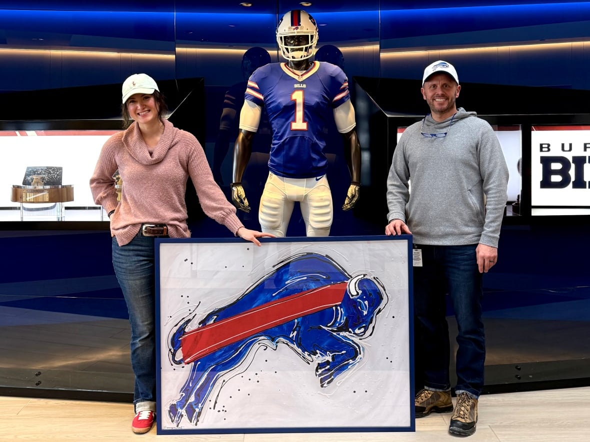 A man and woman stand with a painting of a blue buffalo.