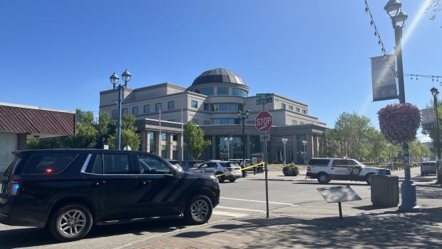 Sheriffs, police and bylaw officers respond to a potential bomb threat at the Prince George courthouse on Aug. 21, 2025. Police and sheriff vehicles around a courthouse, with roads blocked by police tape.