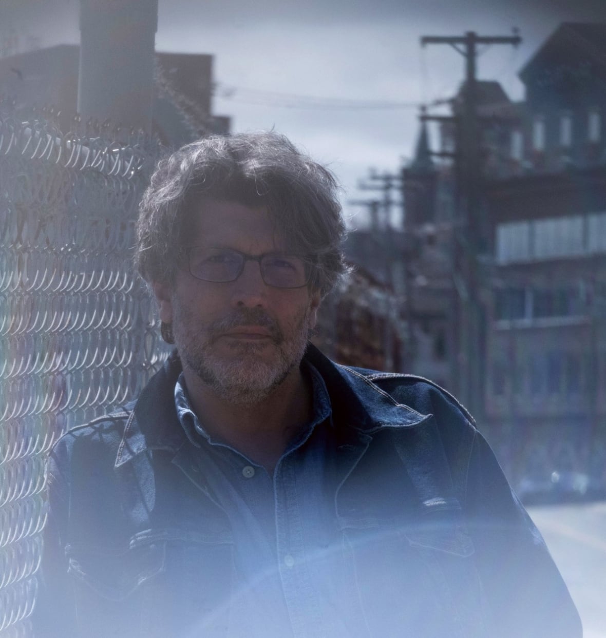 A man leaning against a fence.